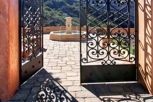 Custom iron gates open onto the picturesque stone courtyard.